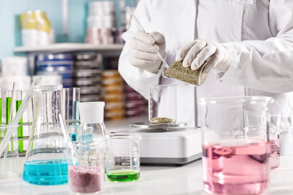 worker-surrounded-with-glass-beakers-filled-with-colorful-liquid.jpg